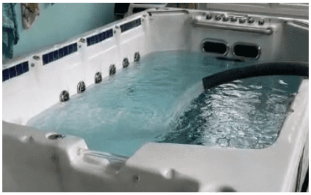 A white hot tub filled with turquoise water and active jets sits on a deck.